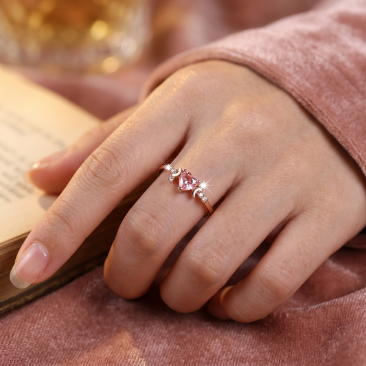 Hand wearing a pink gemstone ring with a blurred background