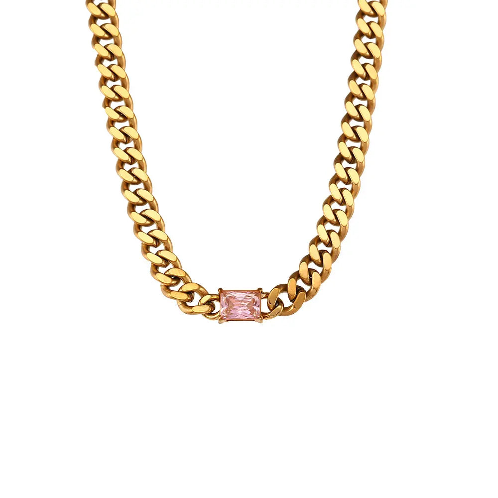 Gold chain necklace with a pink gemstone on a white background