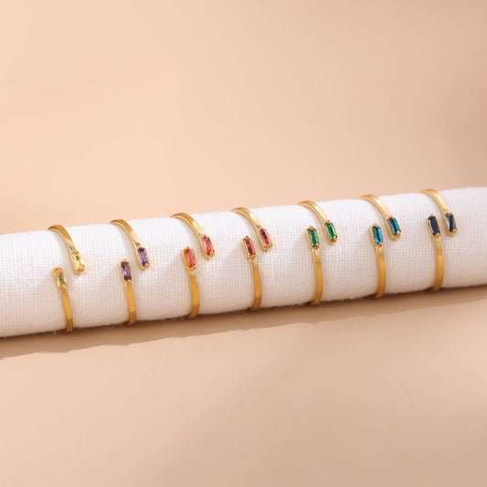 Set of gold bracelets with colorful gemstones on a beige background