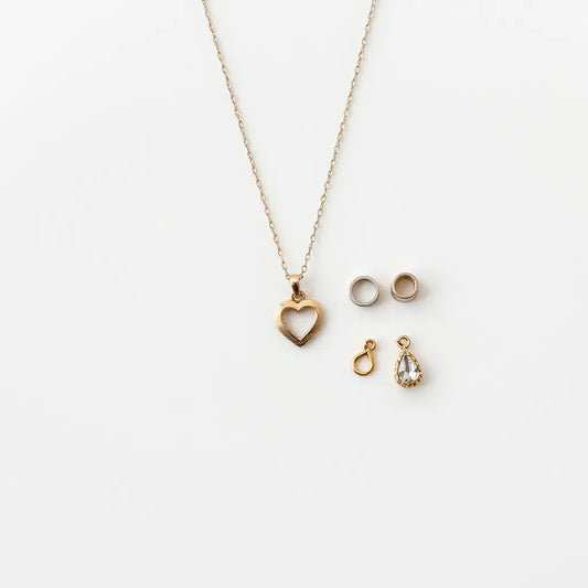 Delicate customizable pendant necklace with interchangeable charm inserts arranged on a light neutral surface