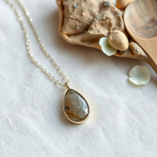Natural stone pendant necklace with a delicate chain and gemstone pendant on light fabric