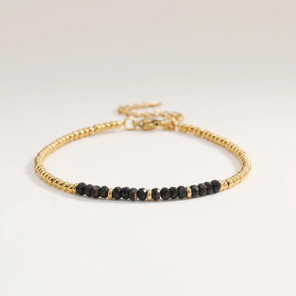 Gold and black beaded bracelet on a light gray background