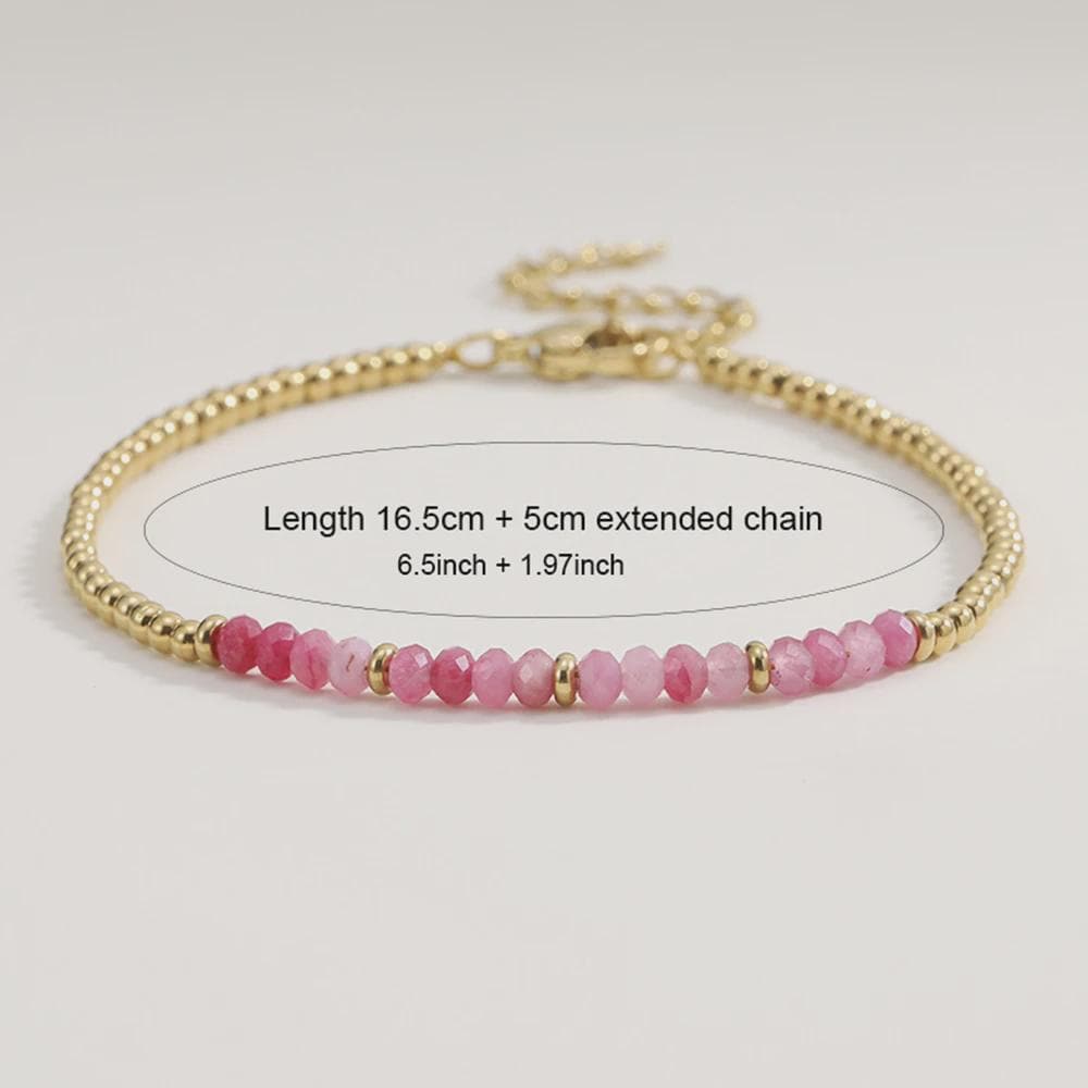 Bracelet with pink beads and gold chain on a light gray background