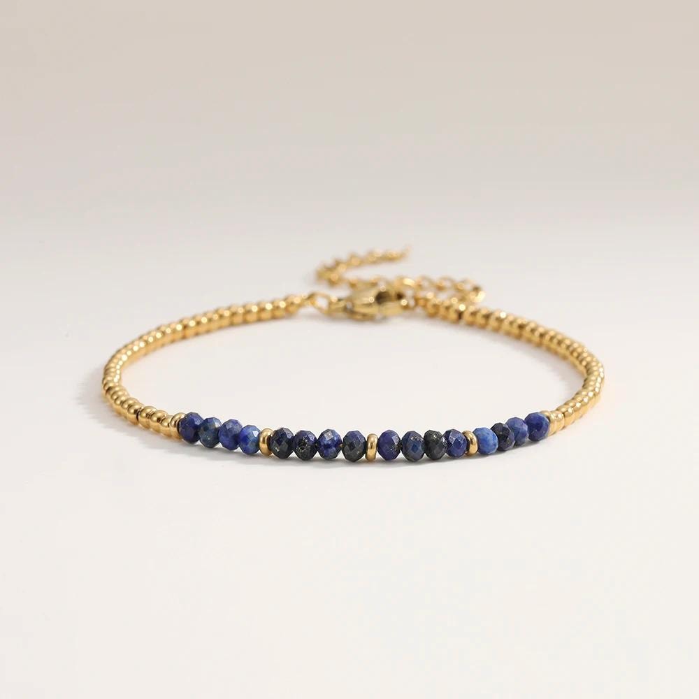 Gold bracelet with blue beads on a light gray background