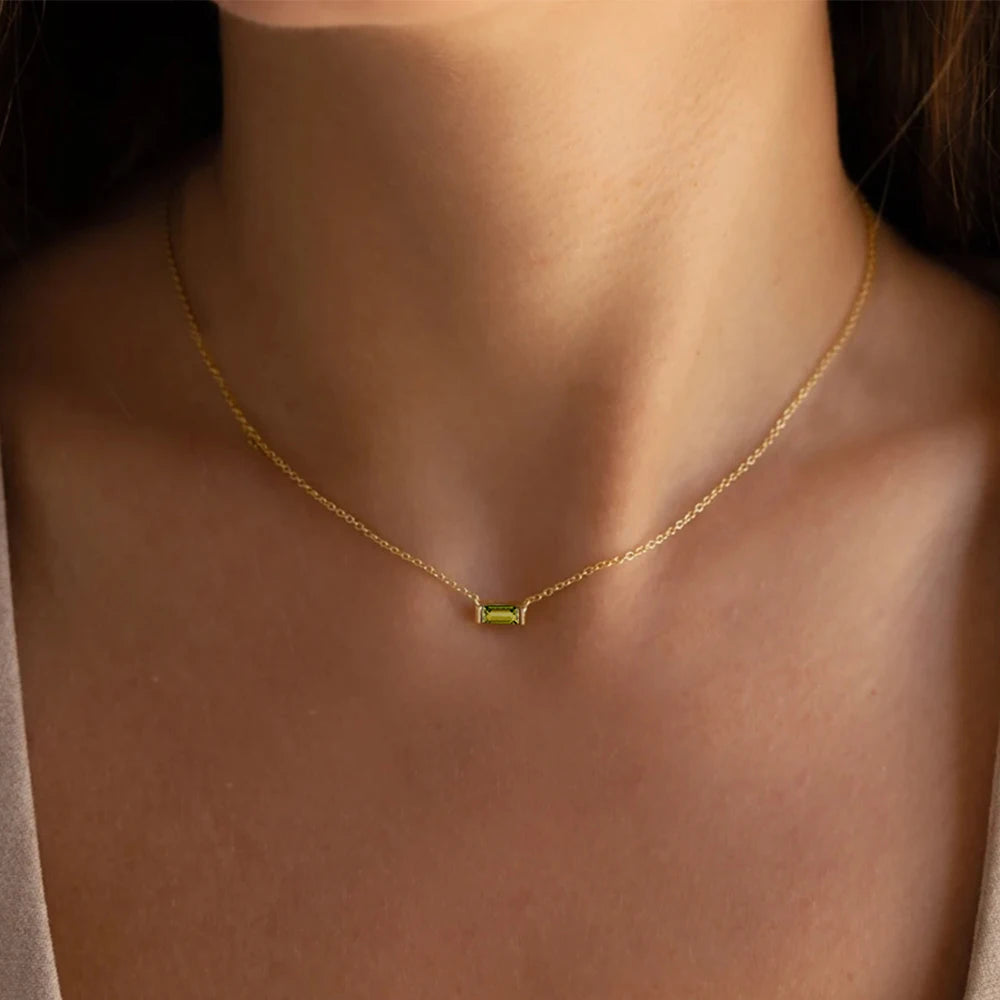 Gold necklace with a green gemstone on a person's neck
