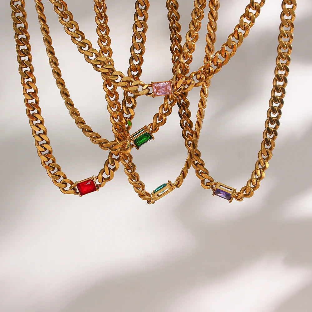 Gold chain necklaces with colorful gemstones on a light background