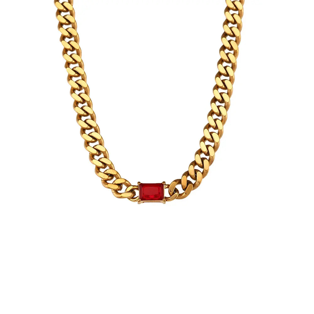 Gold chain necklace with a red gemstone on a white background