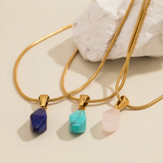 Three gold necklaces with colorful stone pendants on a beige background