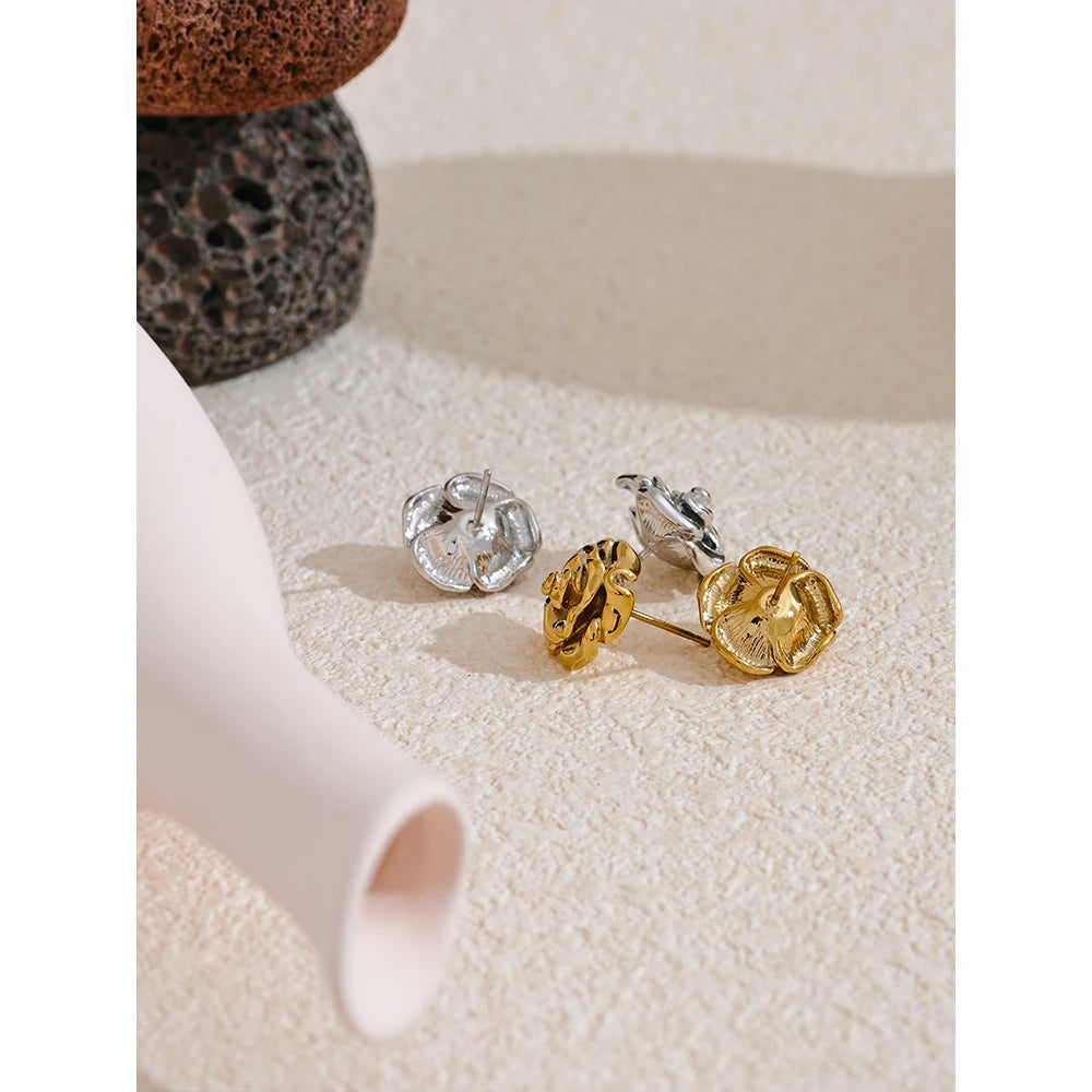 Pair of silver and gold earrings on a textured surface
