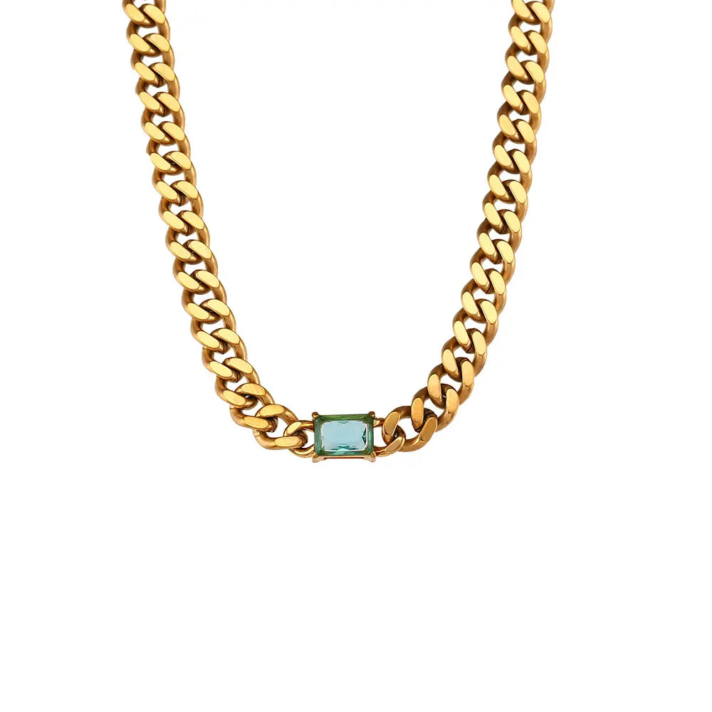 Gold chain necklace with a green gemstone on a white background