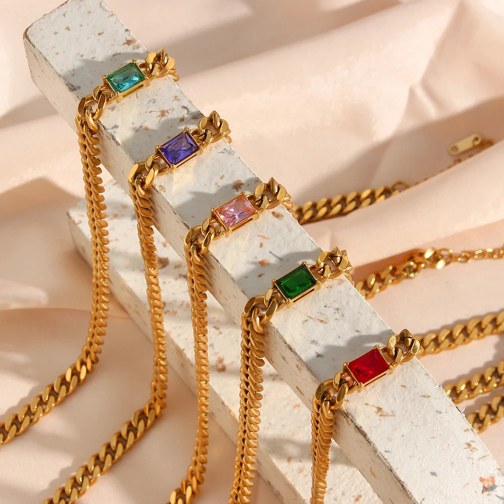 Gold chains with colorful gemstones on a textured surface