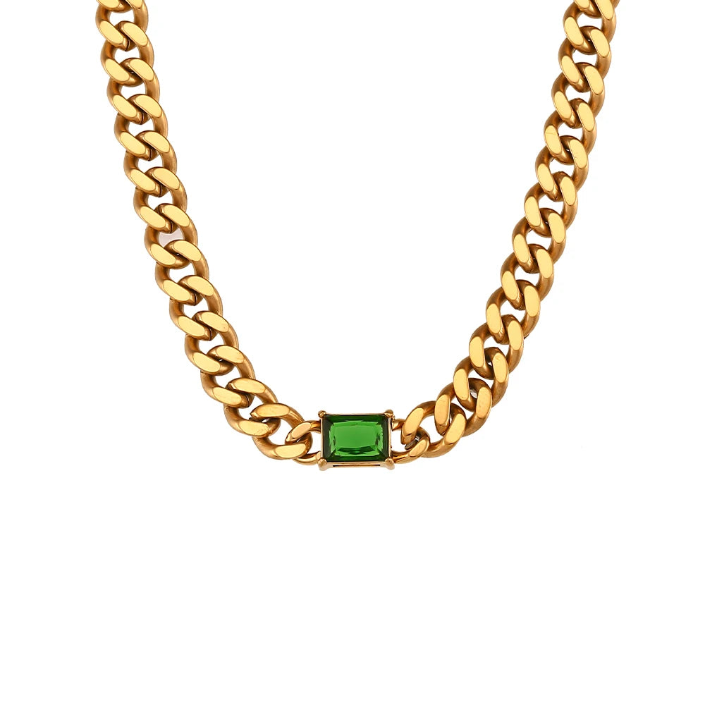 Gold chain necklace with a green gemstone on a white background