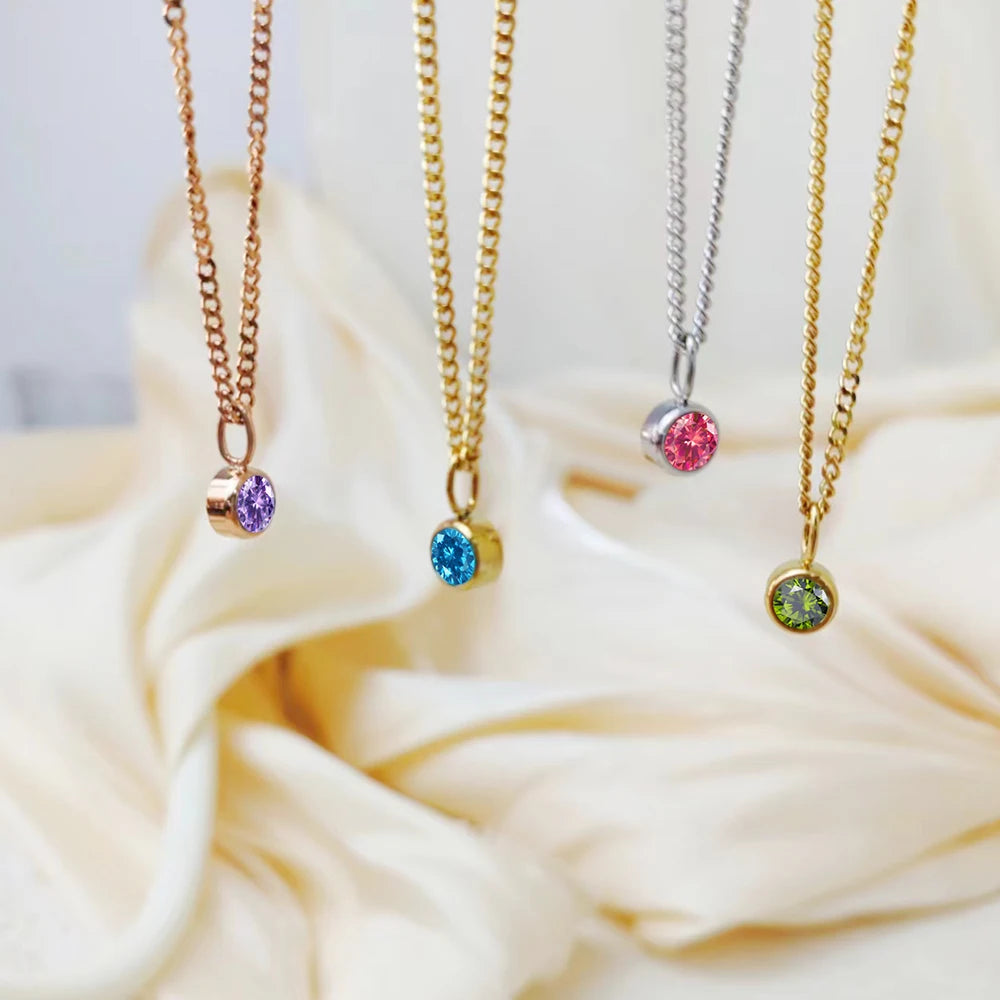 Three necklaces with colorful gemstones on a soft white fabric background