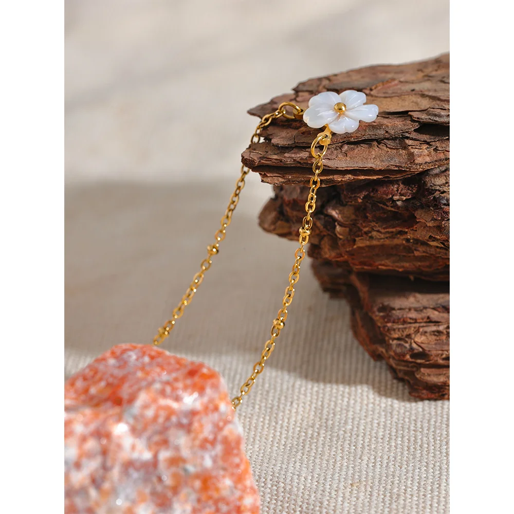 Gold chain earring with floral design on a textured surface