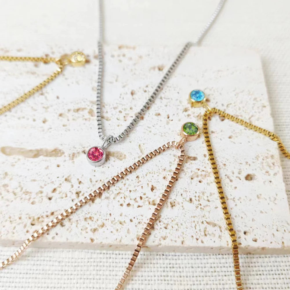Three necklaces with colorful gemstones on a textured white surface