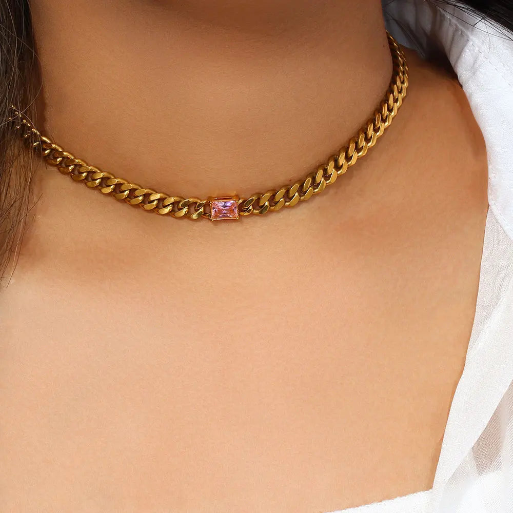 Gold chain necklace with a pink gemstone on a person's neck