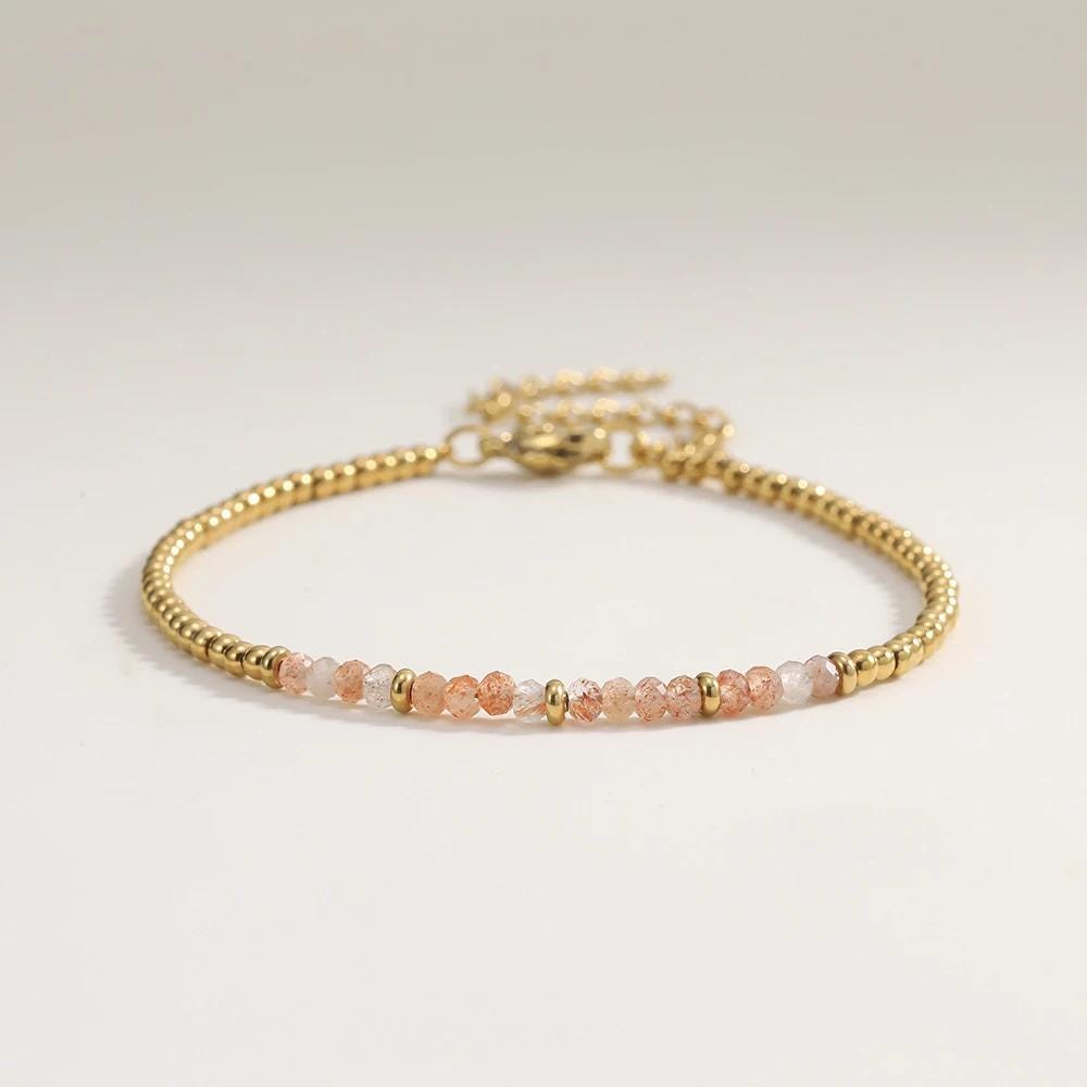 Gold and pink beaded bracelet on a light gray background