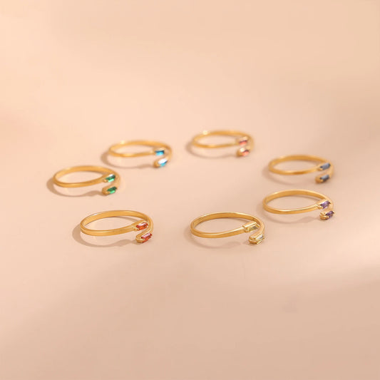 Set of gold rings with colorful gemstones on a beige background